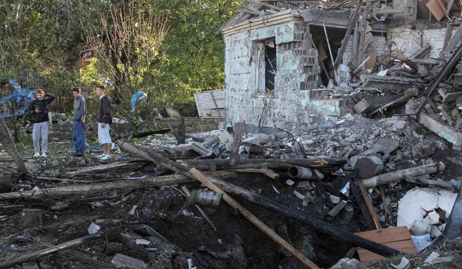 Residents stand near a house damaged by Russian drone strikes in Dnipro