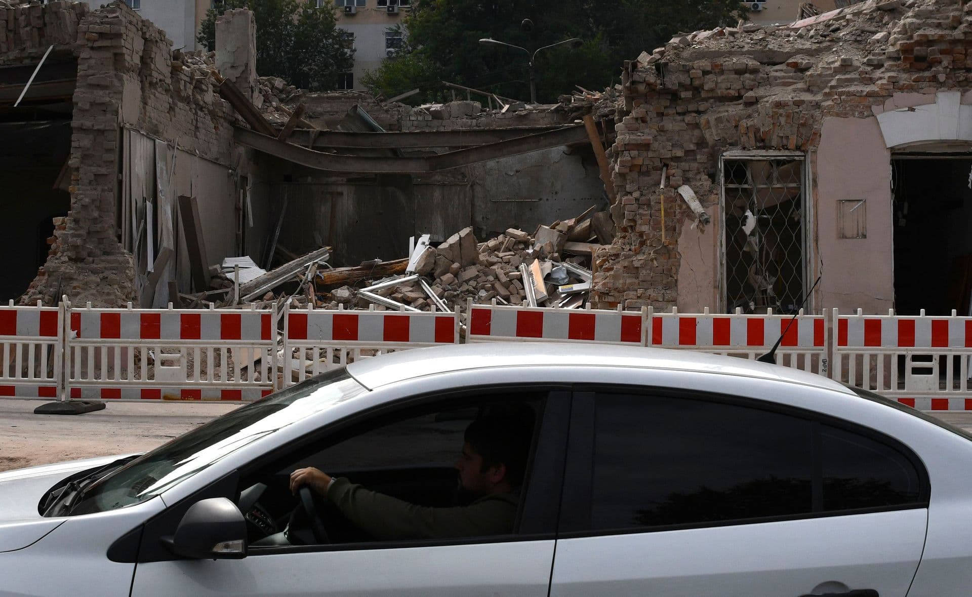 People in a car pass by heavily damaged buildings after latest Russian rocket attack in Dnipro