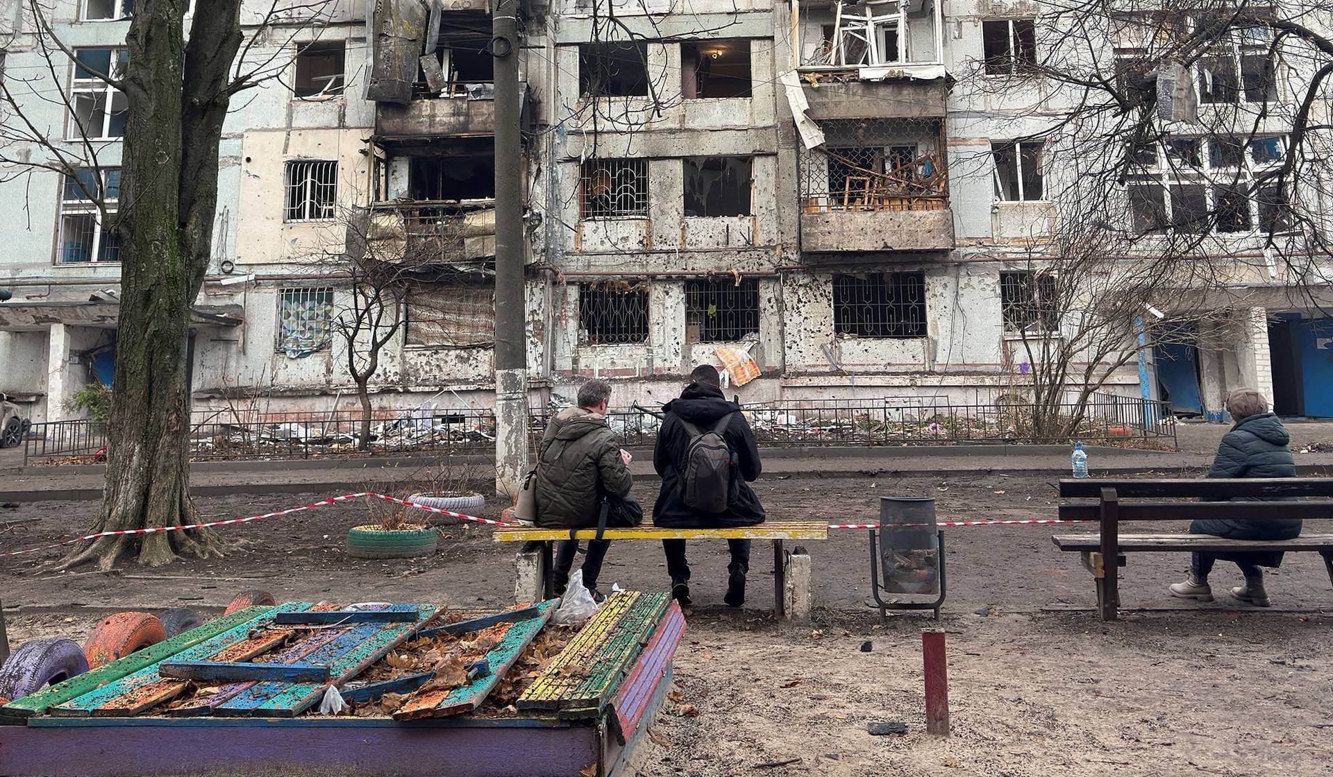 Residents sit near an apartment building damaged during a Russian drone strike in Dnipro