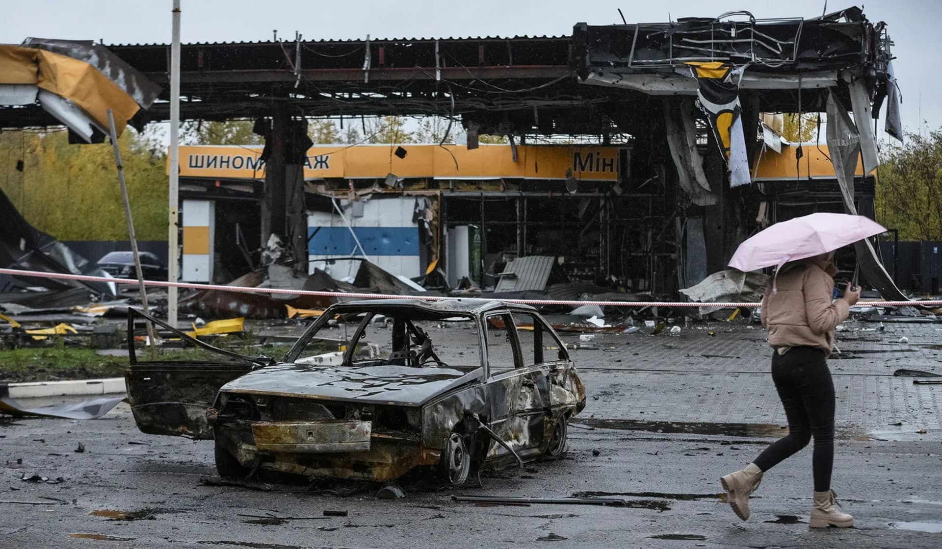 A woman passes by a gas station destroyed by yesterday's Russian military strike in Dnipro
