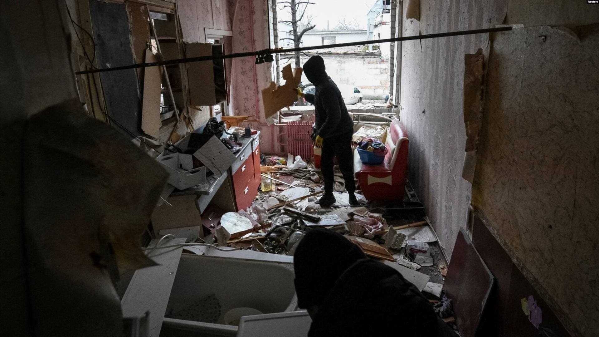 Local residents clean up their apartment in a residential building damaged during a Russian drone strike in Dnipro