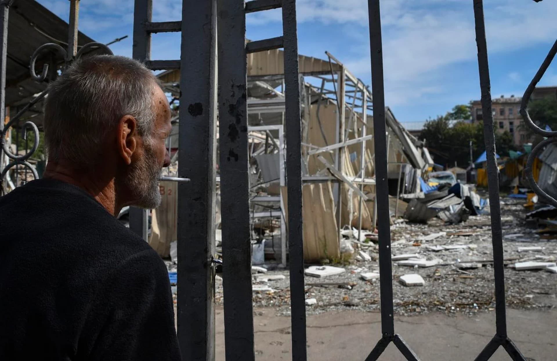 A man stands in front of the gate of local market with heavily damaged shops after latest Russian rocket attack in Dnipro