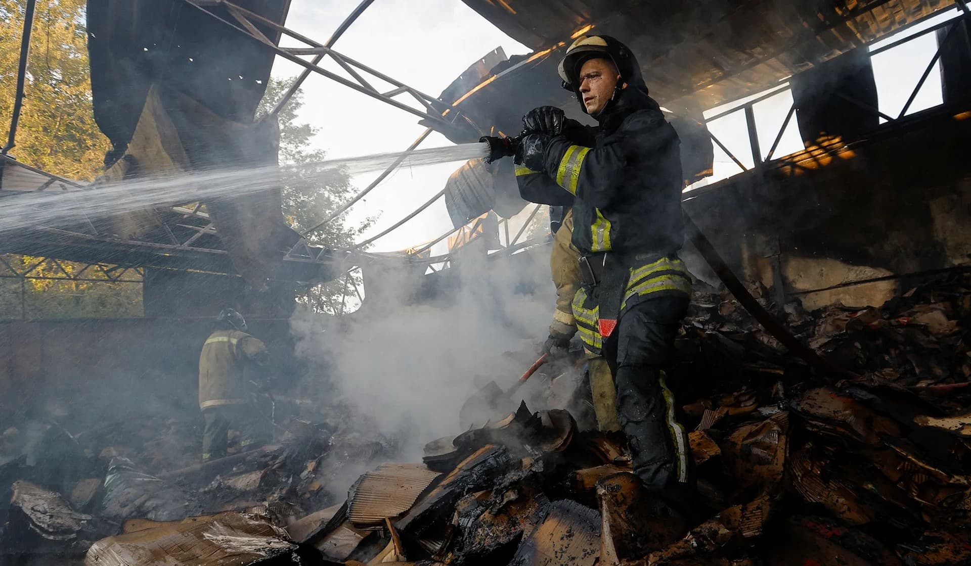 Firefighters work to extinguish fire at a warehouse destroyed in shelling in Donetsk
