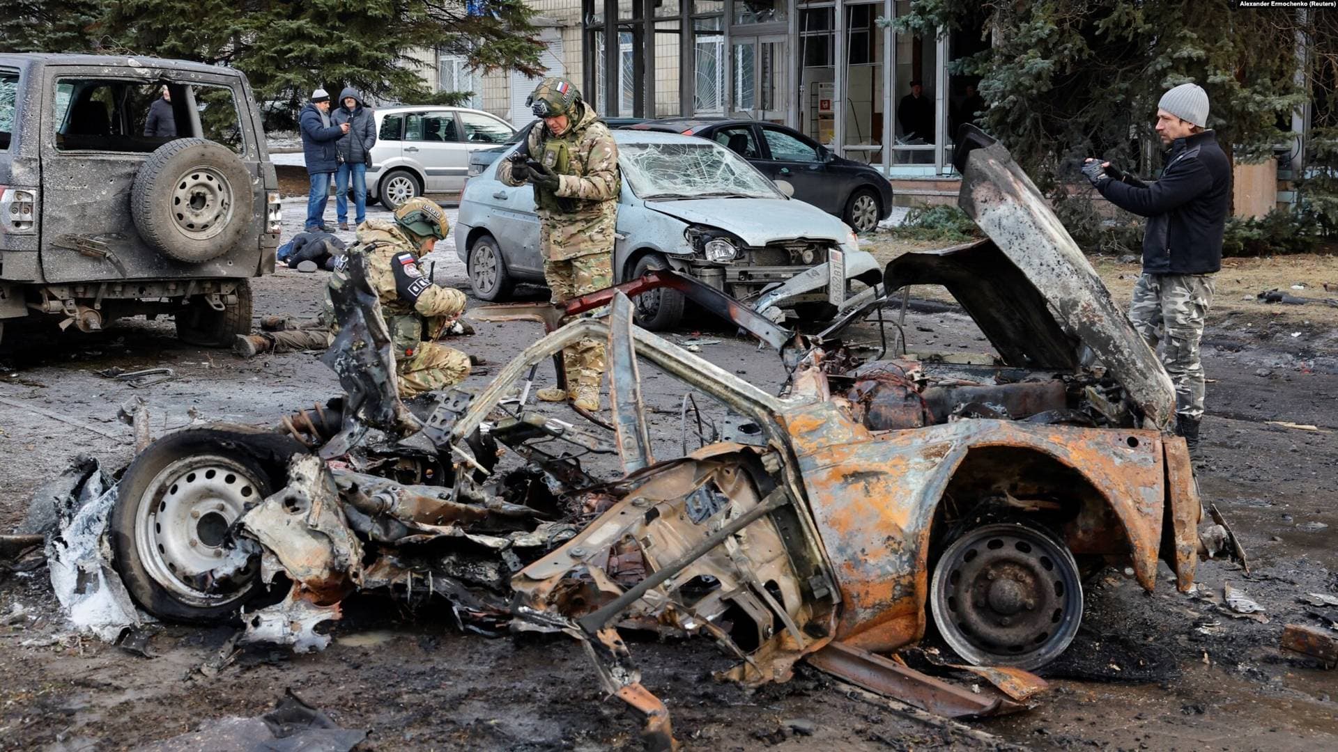 Investigators work outside a damaged building near destroyed cars and the bodies of victims killed by shelling in Donetsk