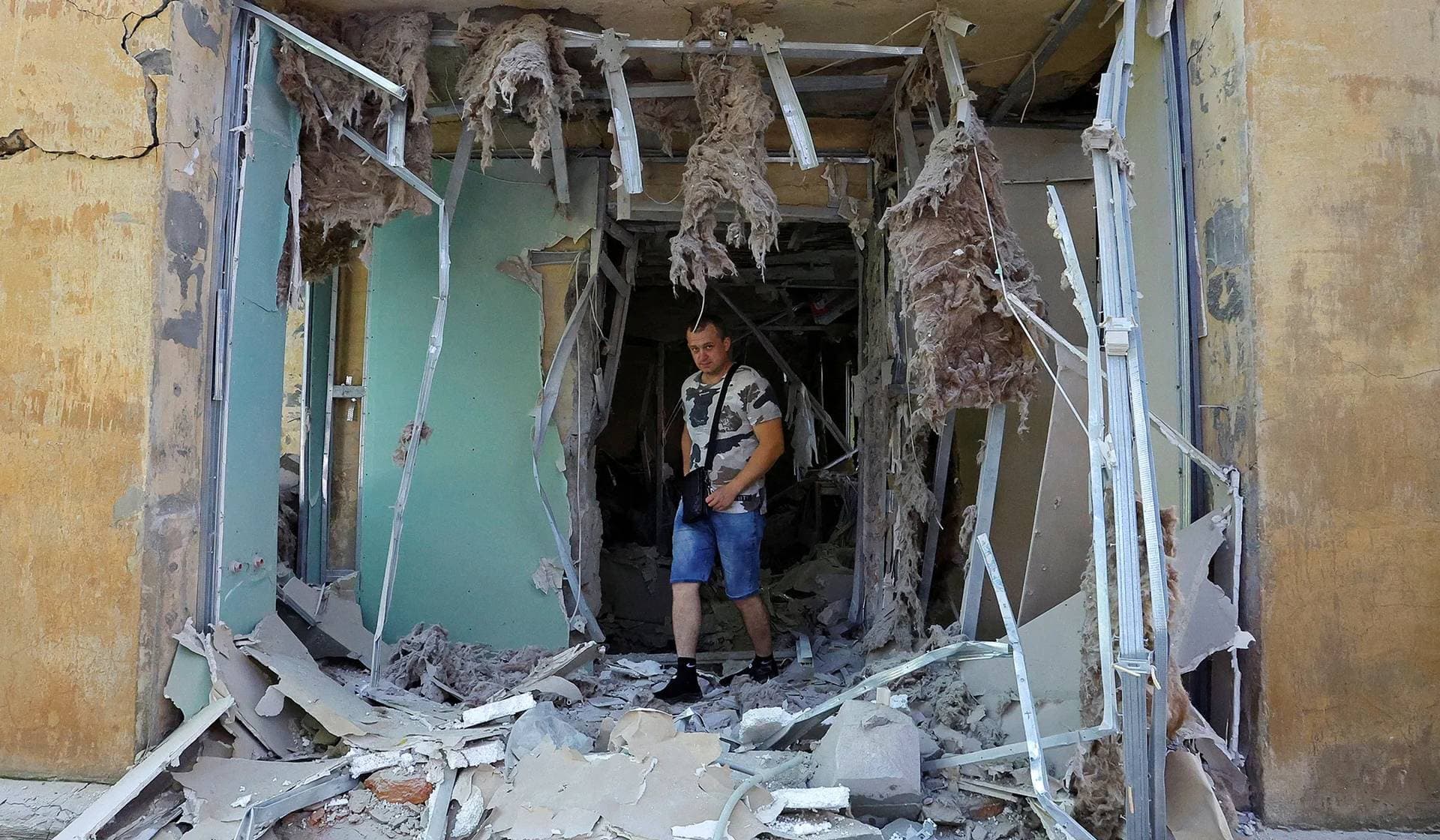A local resident walks through his neighbors' apartment damaged by recent shelling in Donetsk