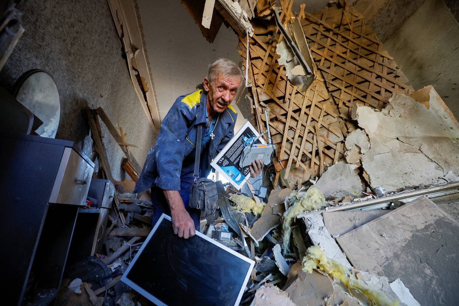 A man carries belongings inside a house heavily damaged by recent shelling  in Donetsk