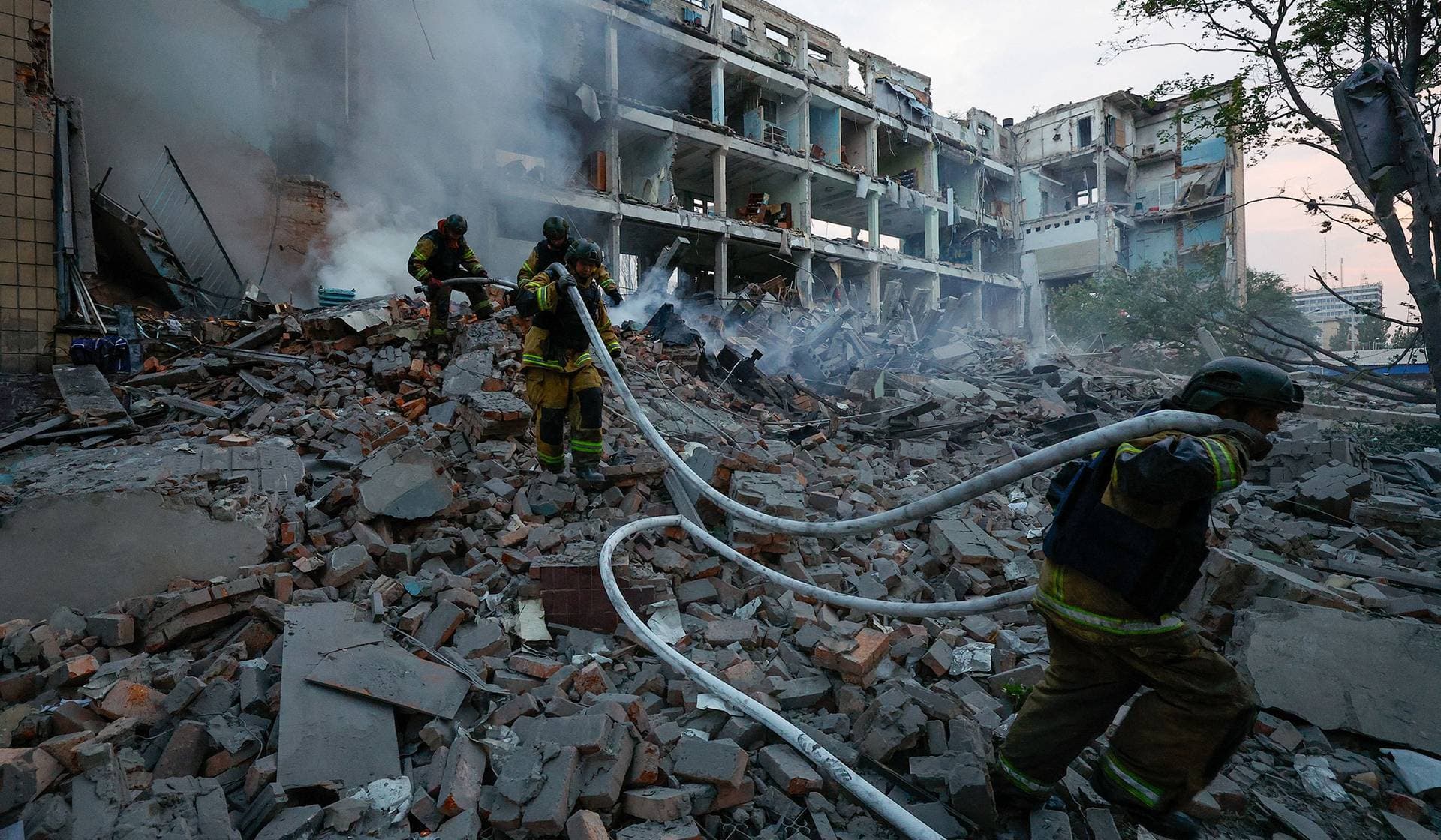 Firefighters work at a destroyed building following a Ukrainian strike in Donetsk