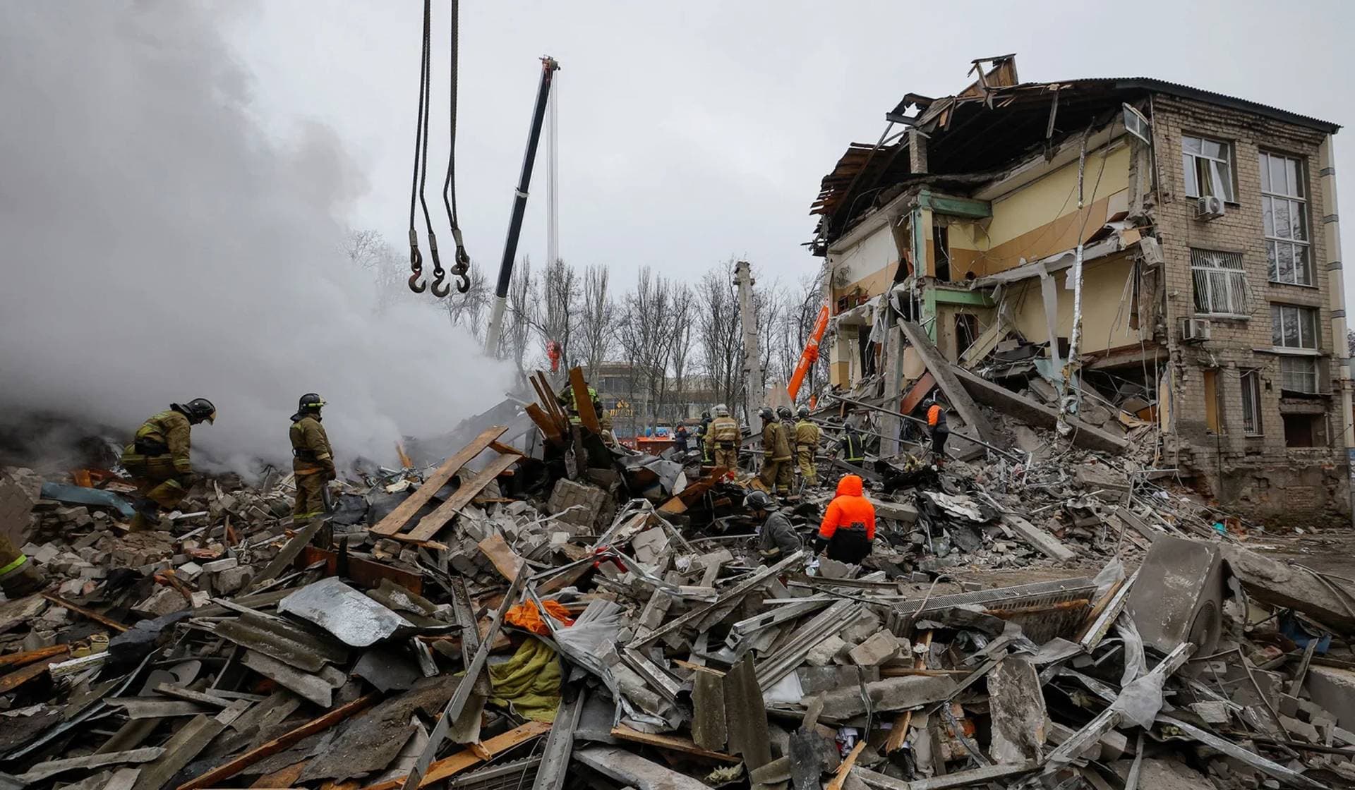 Emergency personnel work among debris at the site where a building was heavily damaged in recent shelling in Donetsk