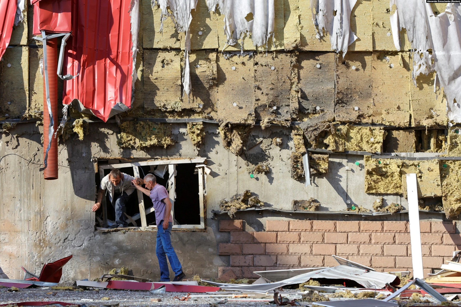 A man climbs out of a damaged residential building following shelling in Donetsk