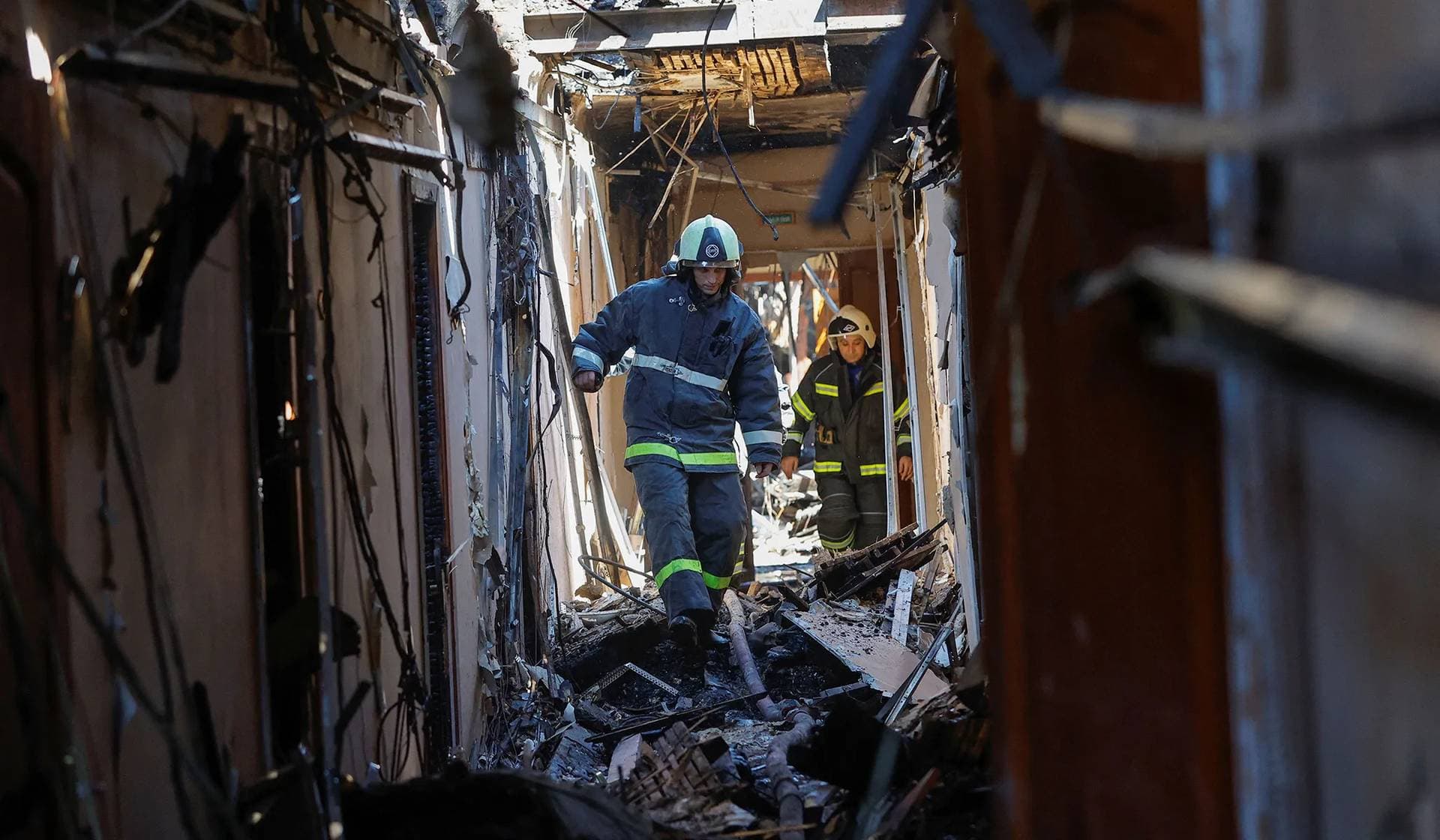 Firefighters walk along a burned-out corridor of the University of Economics and Trade, which was reportedly hit by shelling, in Donetsk