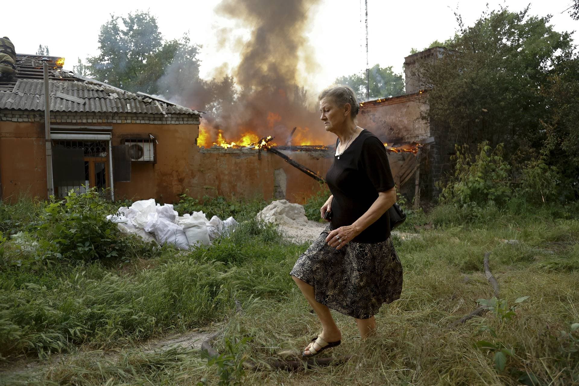 A woman runs from a house that's on fire after shelling in Donetsk