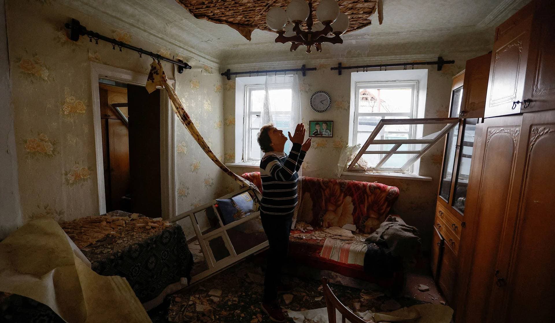 Local resident reacts inside her house destroyed by shelling in Donetsk