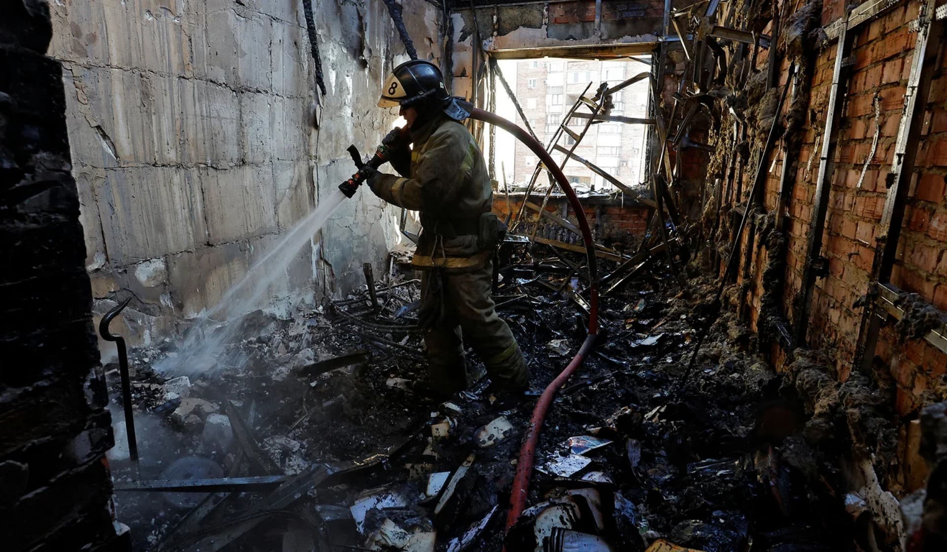 A firefighter works inside a destroyed apartment of a residential building hit by shelling in Donetsk