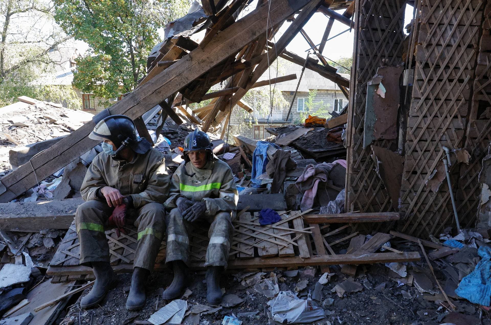 Rescuers sit amid debris of a house heavily damaged by recent shelling in Donetsk
