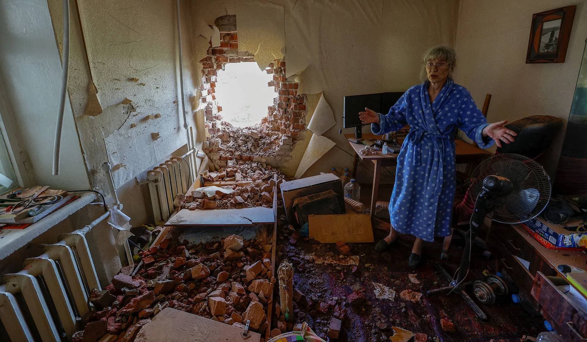 Local resident removes debris inside her apartment hit by shelling in Donetsk