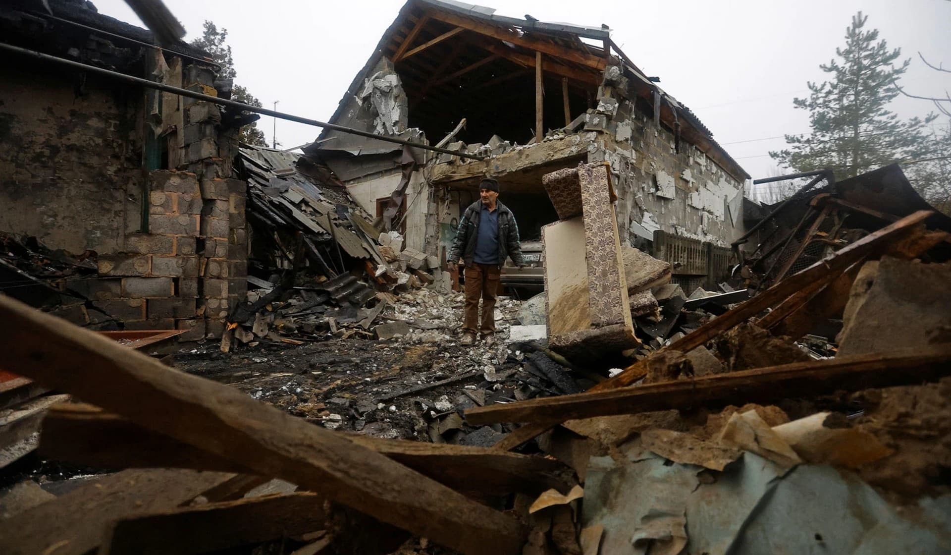 Local resident Amiram stands next to his friend's house that was destroyed by recent shelling in Donetsk