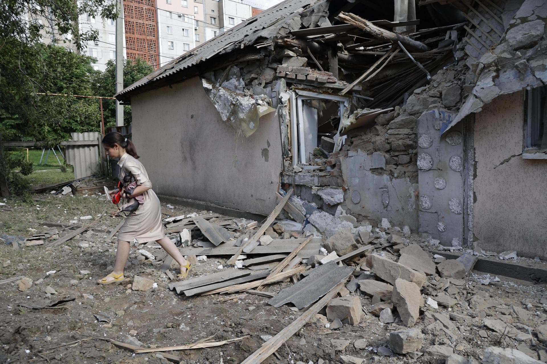 A girl carries a dog as she walks past a house damaged from shelling in Donetsk