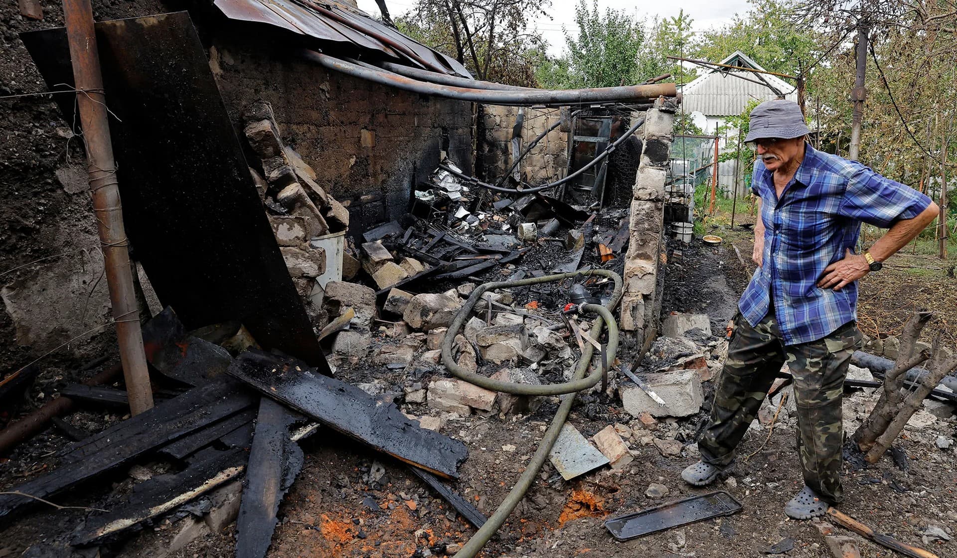Local resident stands next to the ruins of his outbuilding destroyed by recent shelling in Donetsk