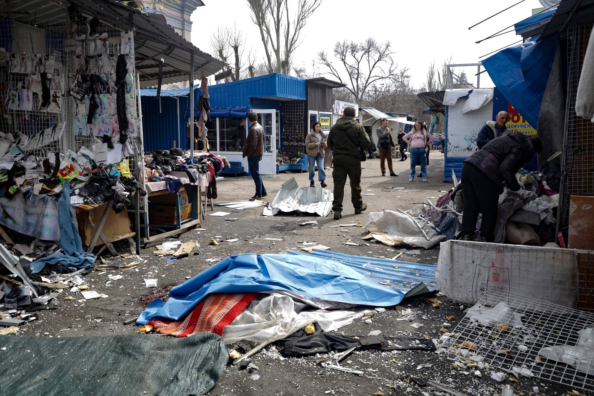 A lifeless body covered by plastic lies on the ground at a street market after the shelling in Donetsk