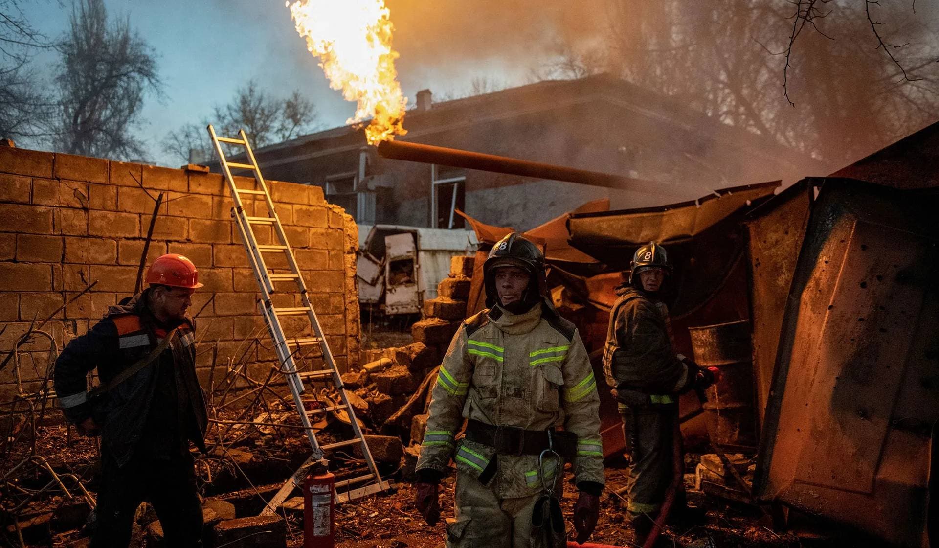 Rescuers work to put out fire outside a damaged residential building hit by recent shelling in Donetsk