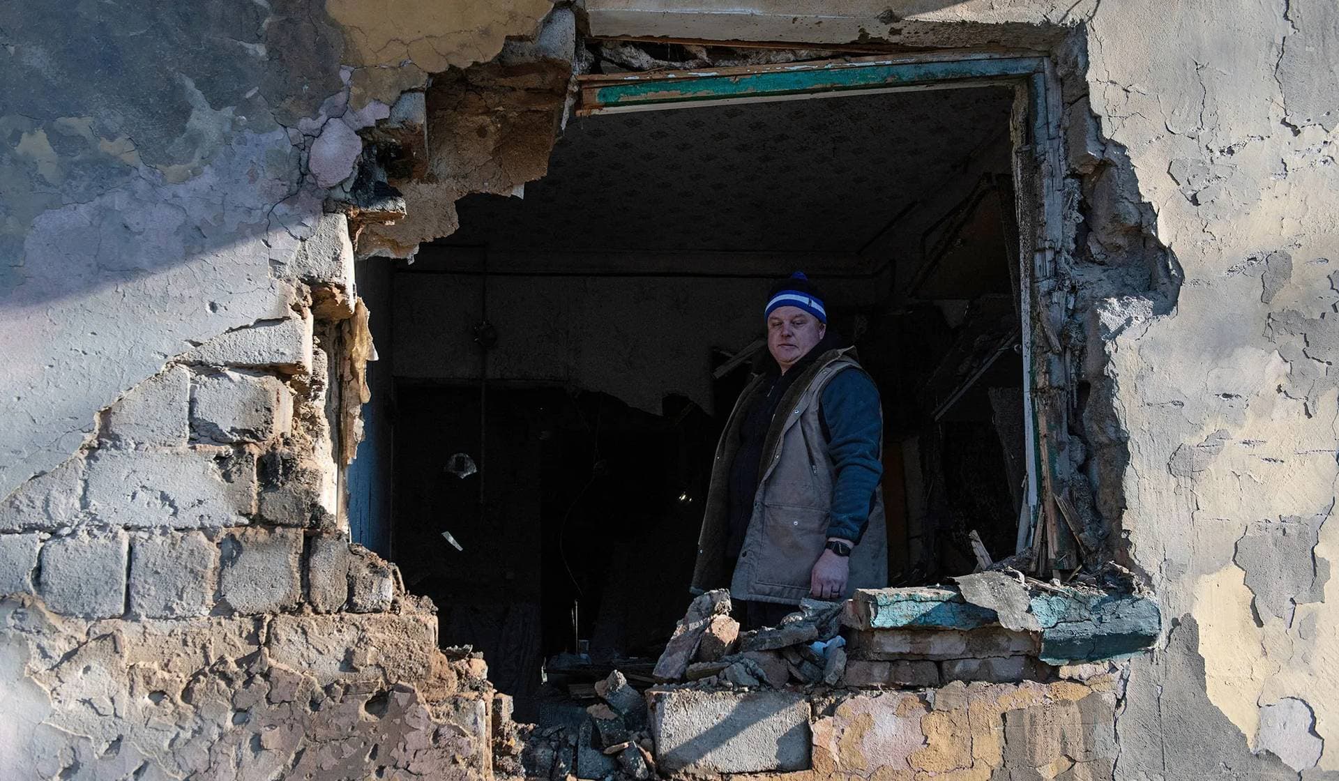 A resident stands inside an apartment damaged by recent shelling in Donetsk