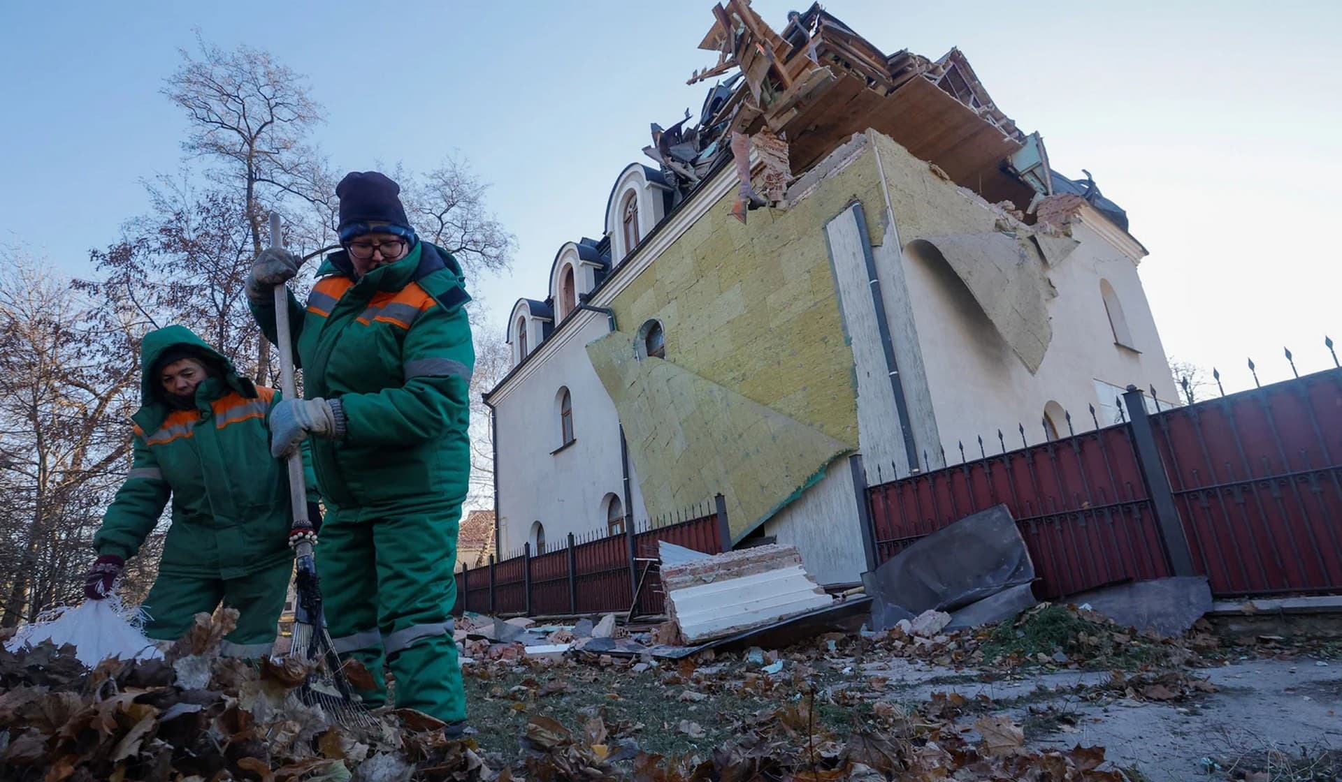 Municipal workers remove debris outside a building on the premises of a local church which was damaged in shelling in Donetsk