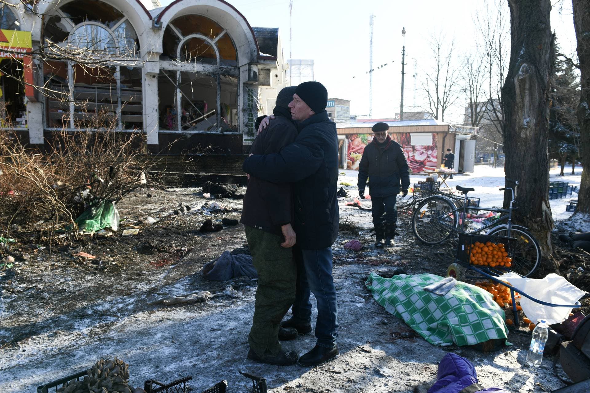 Two men embrace at the scene of a deadly shelling attack in Donetsk