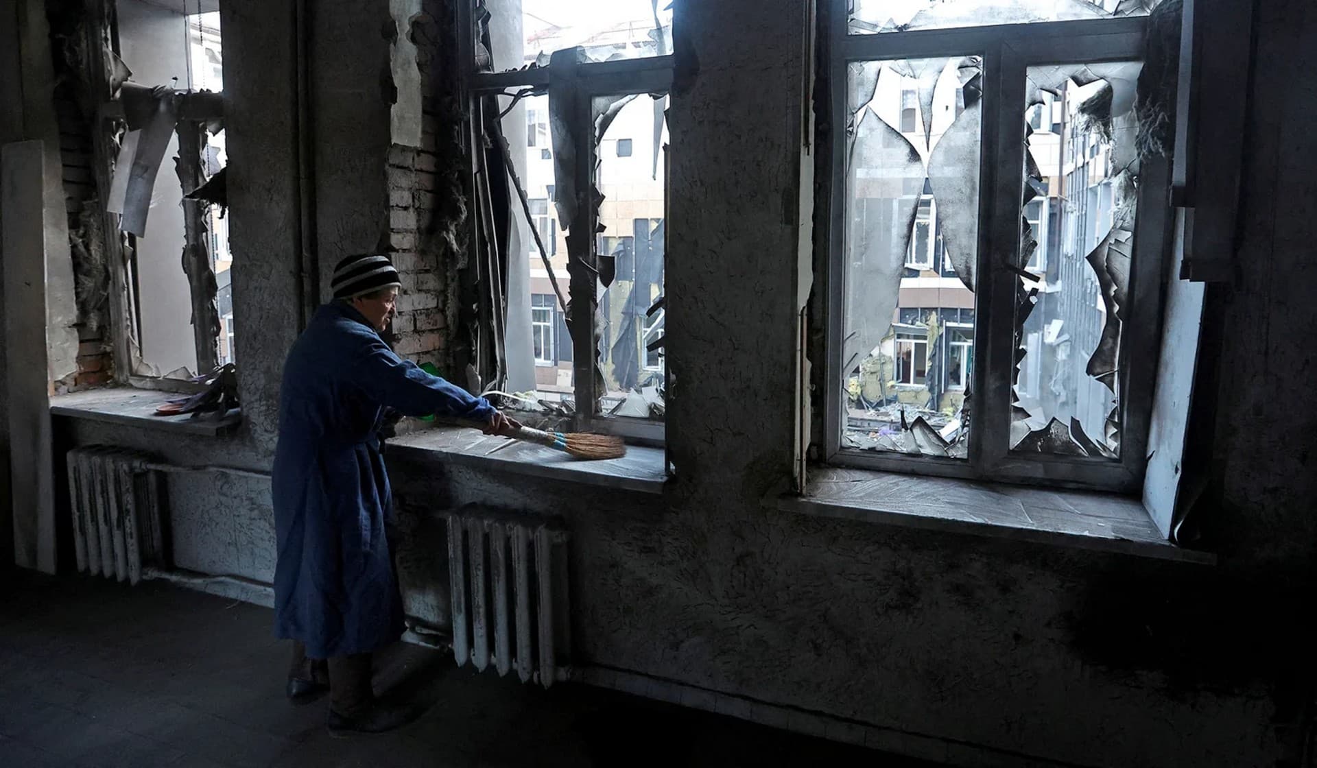 A woman removes broken glass inside a hospital damaged by recent shelling in Donetsk