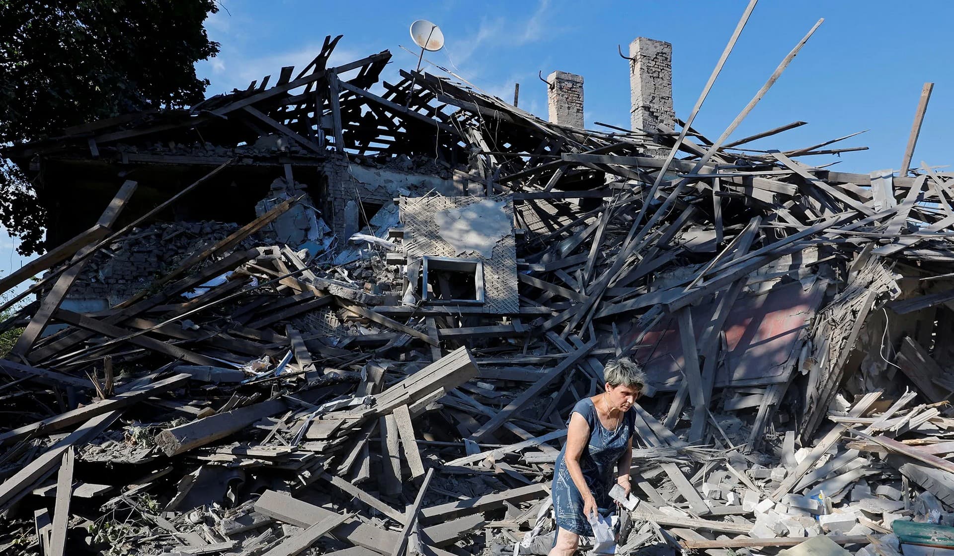 A woman searches for her belongings in the ruins of a house destroyed by recent shelling in Donetsk