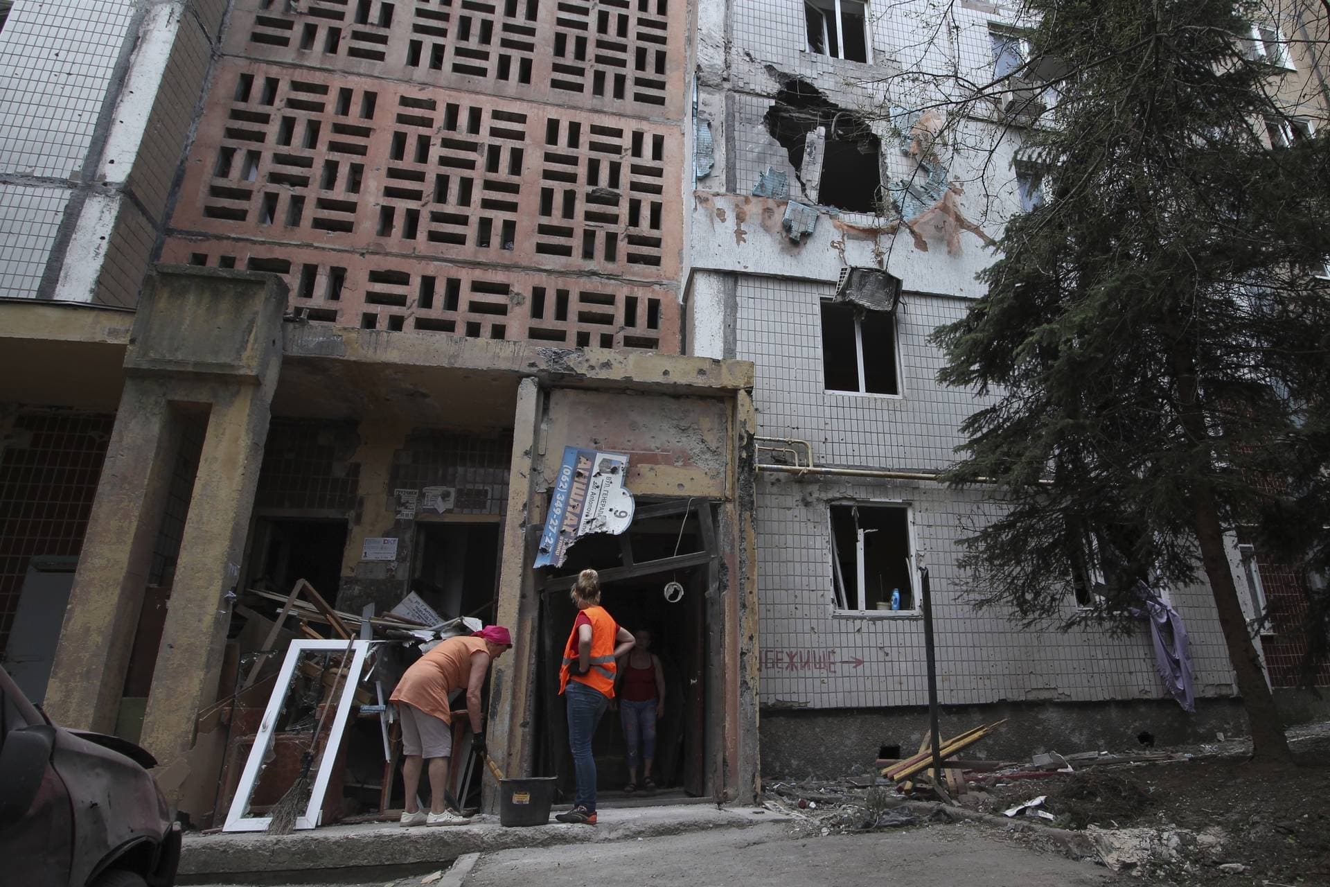 Local residents stand at a damaged the shelling apartment building in the Petrovsky district of Donetsk