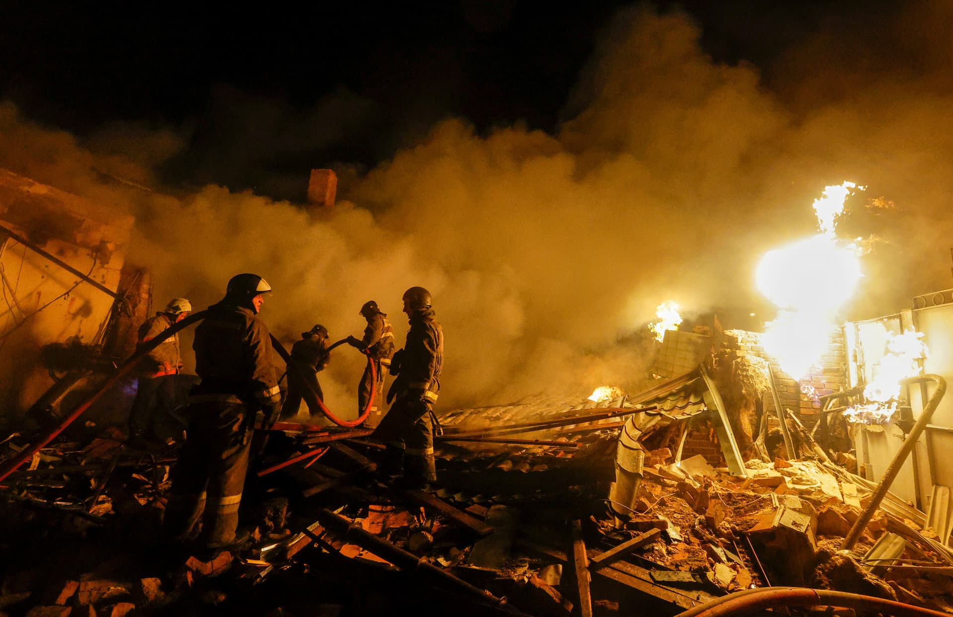 Firefighters work to extinguish fire amidst debris of a residential building destroyed in shelling in in Donetsk