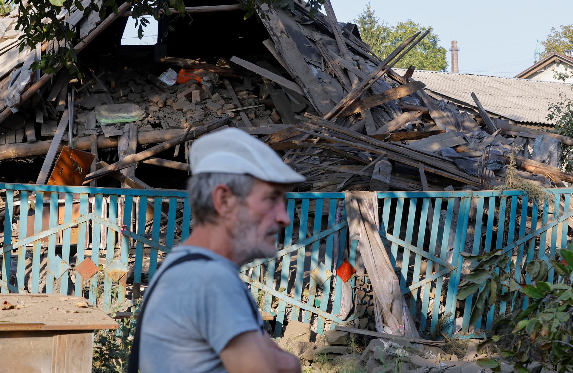 A man walks past a house destroyed by recent shelling in Donetsk