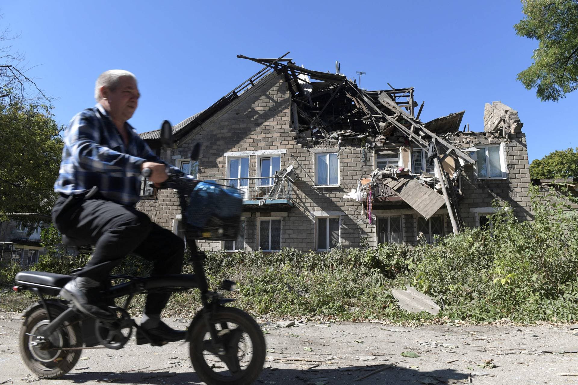 A man drives past a ruined building in Russian-controlled Donetsk after recent shelling.