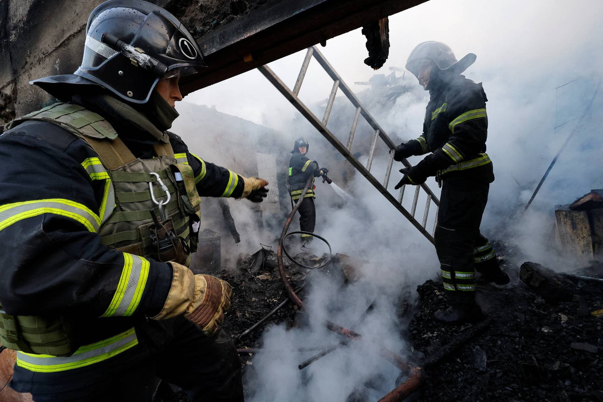 Firefighters work amid debris of a building hit by a rocket attack in Donetsk