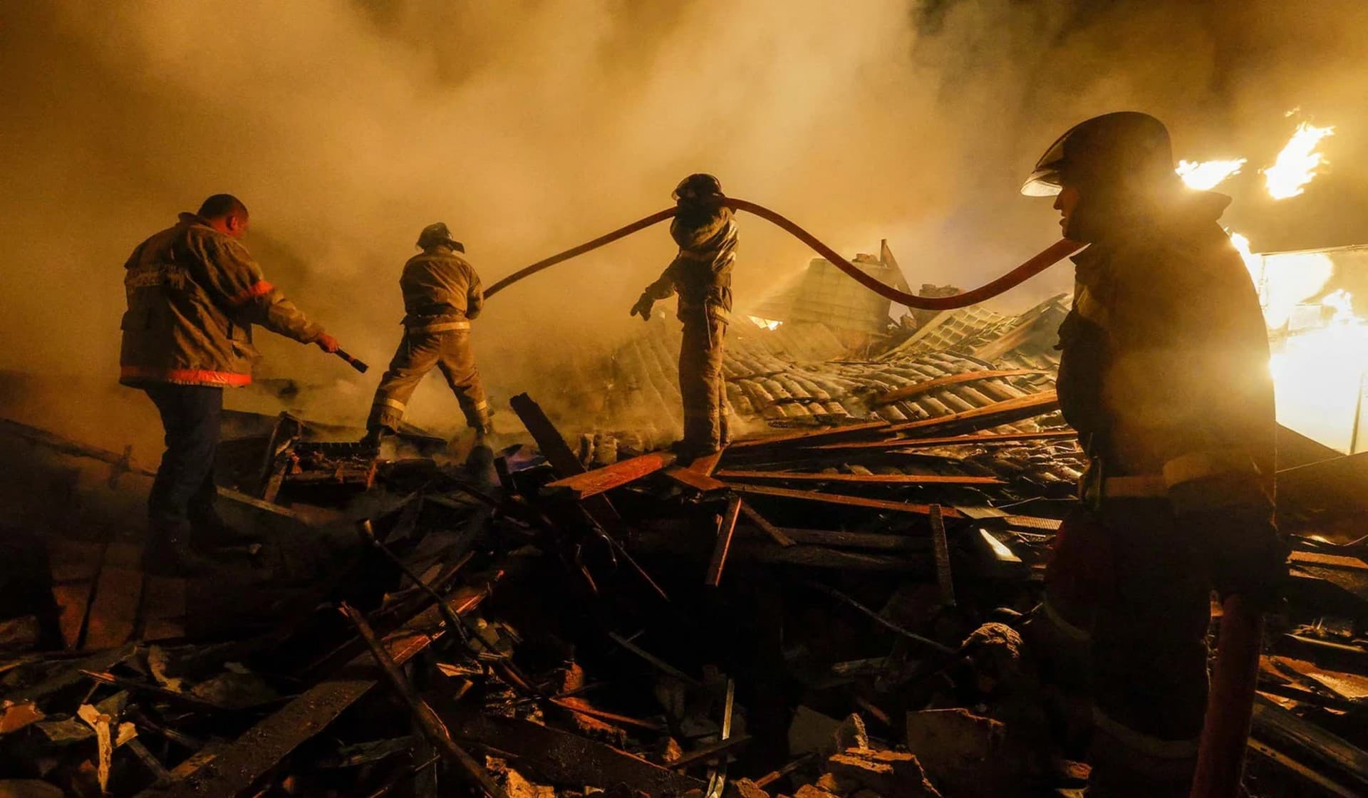 Firefighters work to extinguish fire amidst debris of a residential building destroyed in shelling in in Donetsk