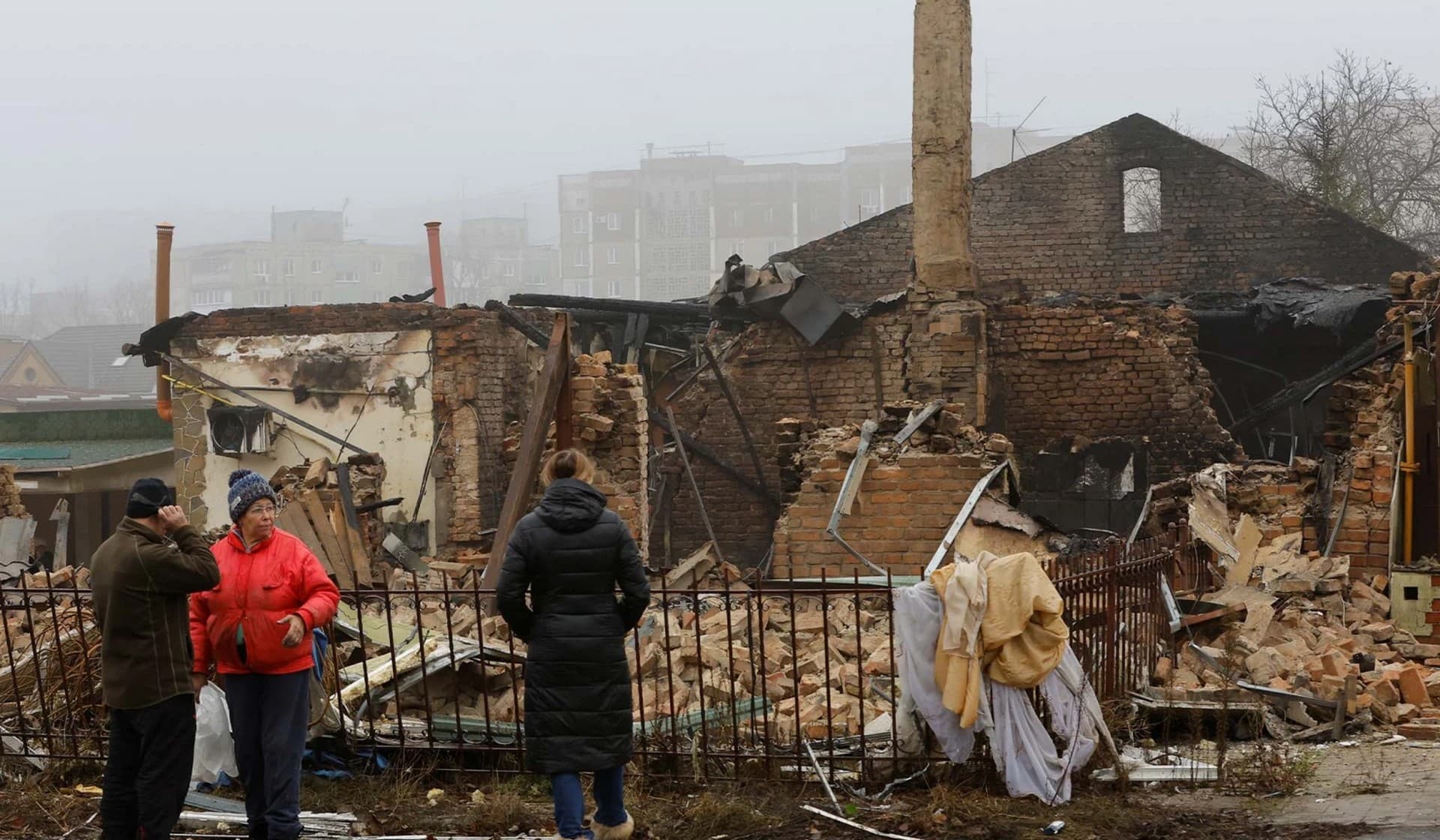 People gather near a residential building destroyed in recent shelling in Donetsk region