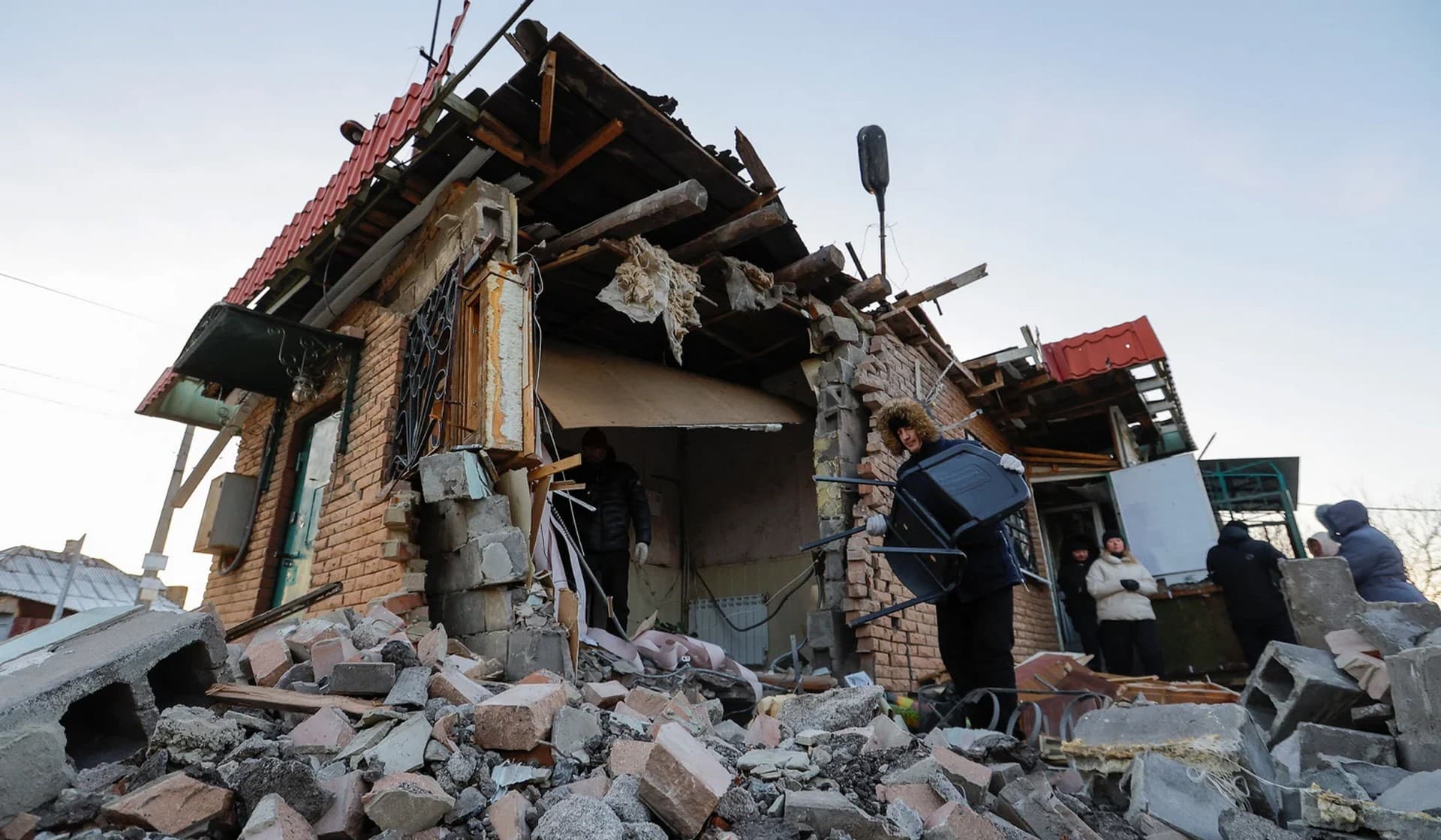 Local residents remove debris and carry belongings out of a shop destroyed in recent shelling in Donetsk