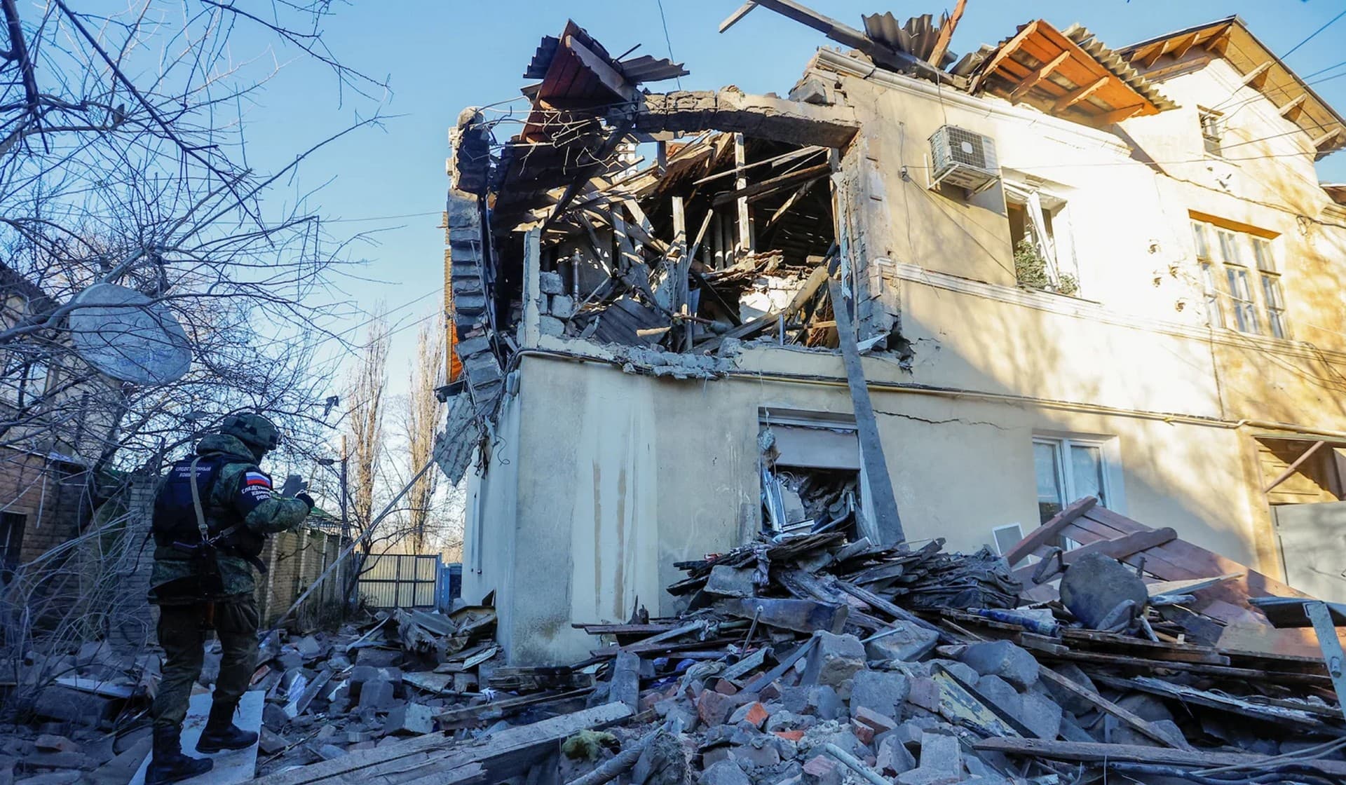 A Russian military investigator works outside a residential building heavily damaged in recent shelling in Donetsk