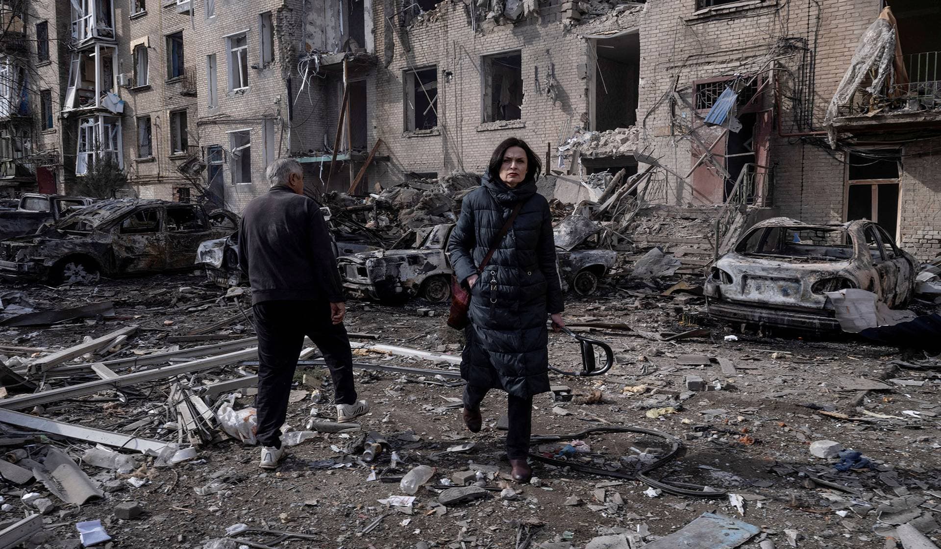 Residents walk at a site of a Russian air strike, in the frontline town of Druzhkivka