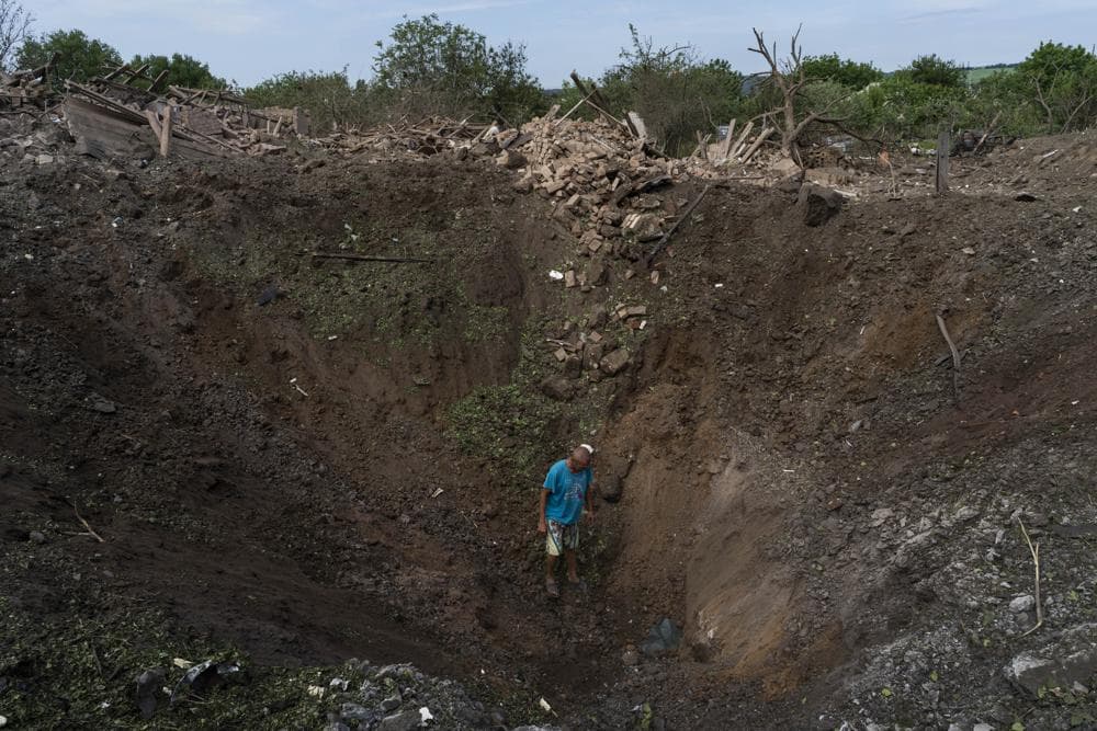 A resident walks into a crater caused by a missile strike in Druzhkivka