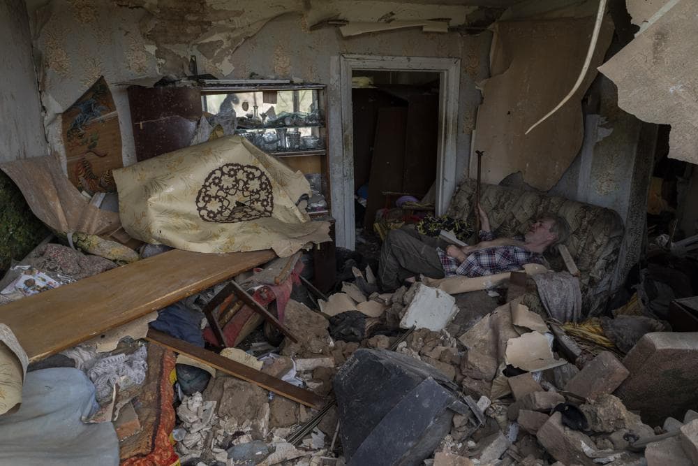 A resident sits on a sofa inside a house damaged after a missile strike in Druzhkivka