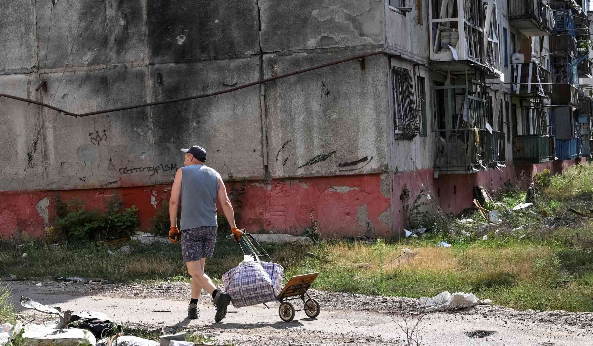 A resident walks near a damaged apartment building in the front-line city of Druzhkivka