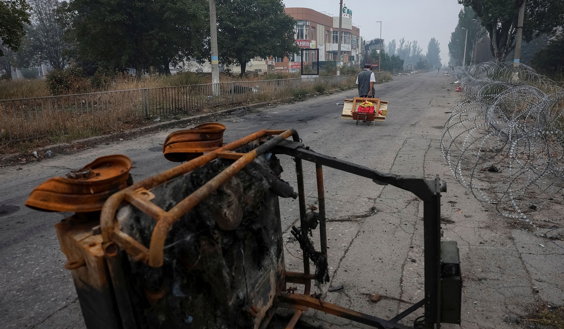 A resident walks on a street protected by razor wire in the frontline town of Druzhkivka