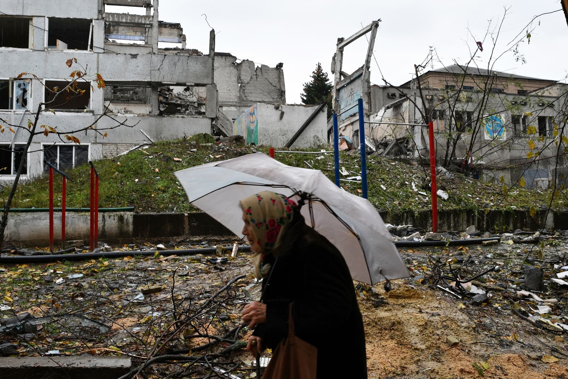 A woman walks past buildings damaged by Russian shelling in Druzhkivka