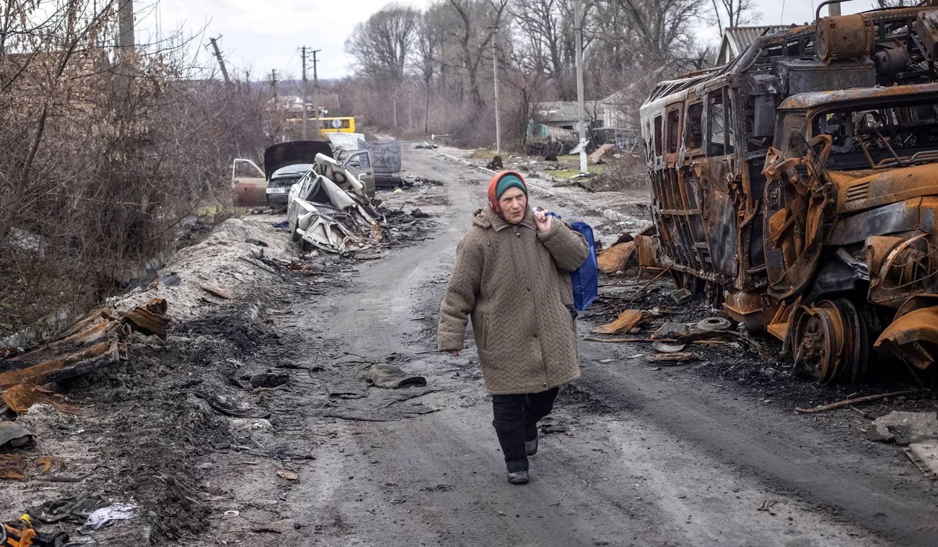 A local resident walks an empty street near destroyed vehicles in the village of Torske