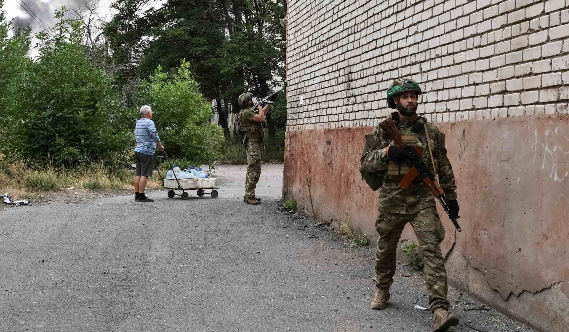 A Ukrainian serviceman fires at a Russian drone as a resident watches nearby in the front-line city of Druzhkivka