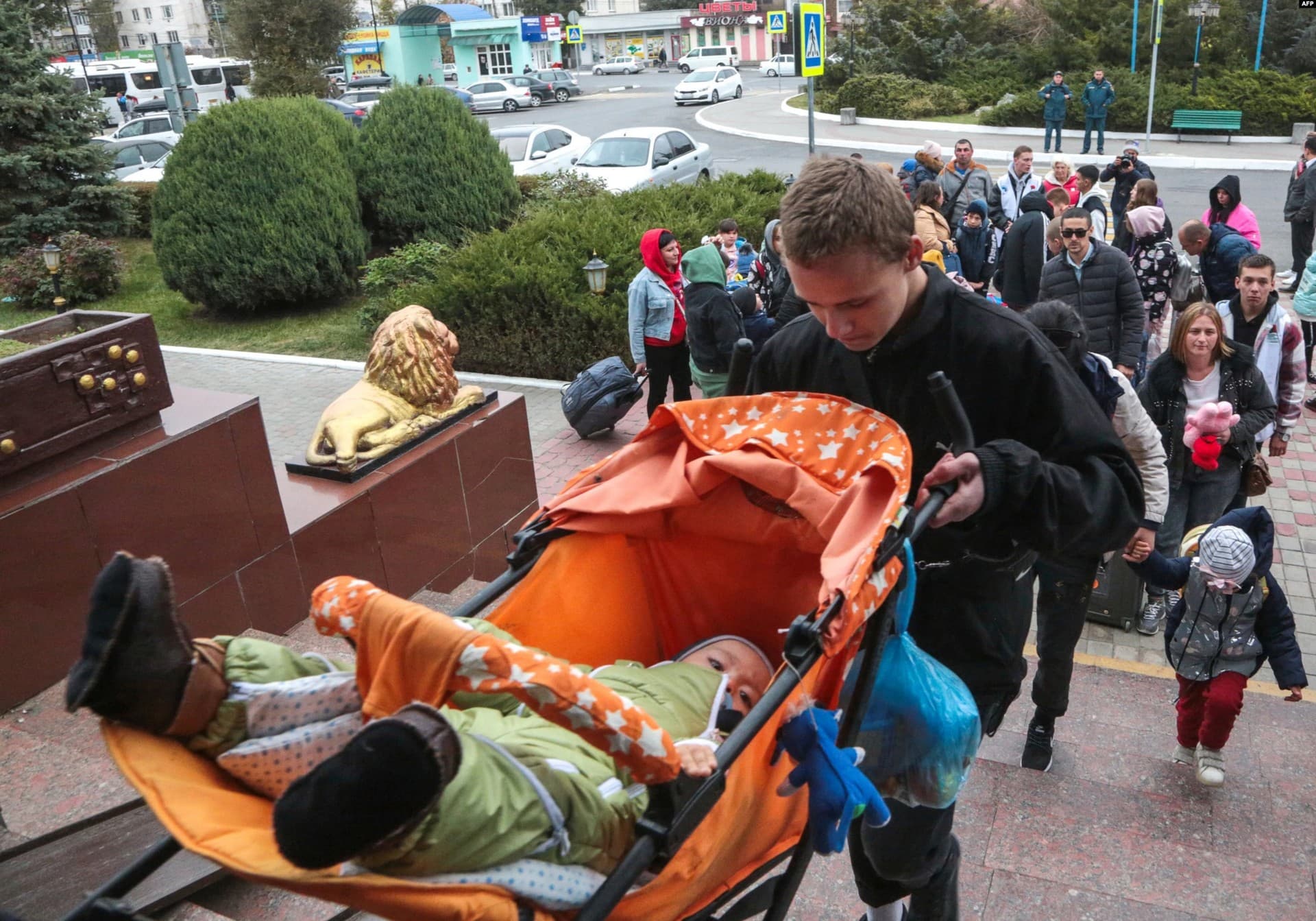 A man carries a baby in a stroller up the stairs of the Dzhankoi train station in Crimea