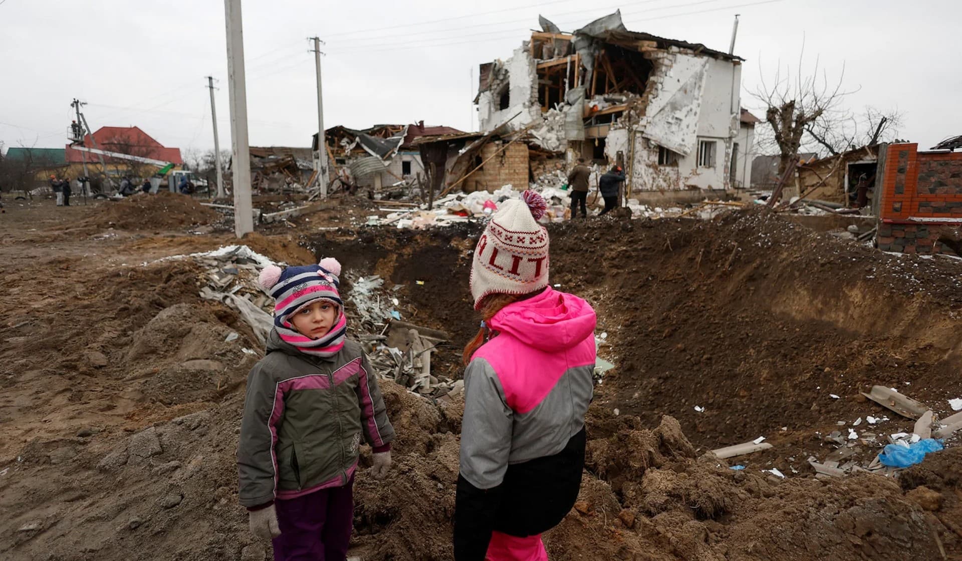 Kids stand next to a crater left by a Russian military strike in Hlevakha