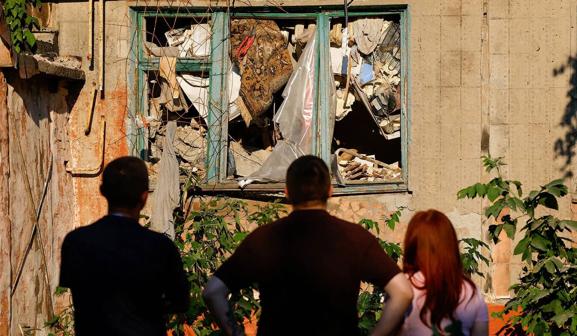 People stand in front of a heavily damaged multi-story residential building following an overnight attack in Horlivka (Gorlovka)