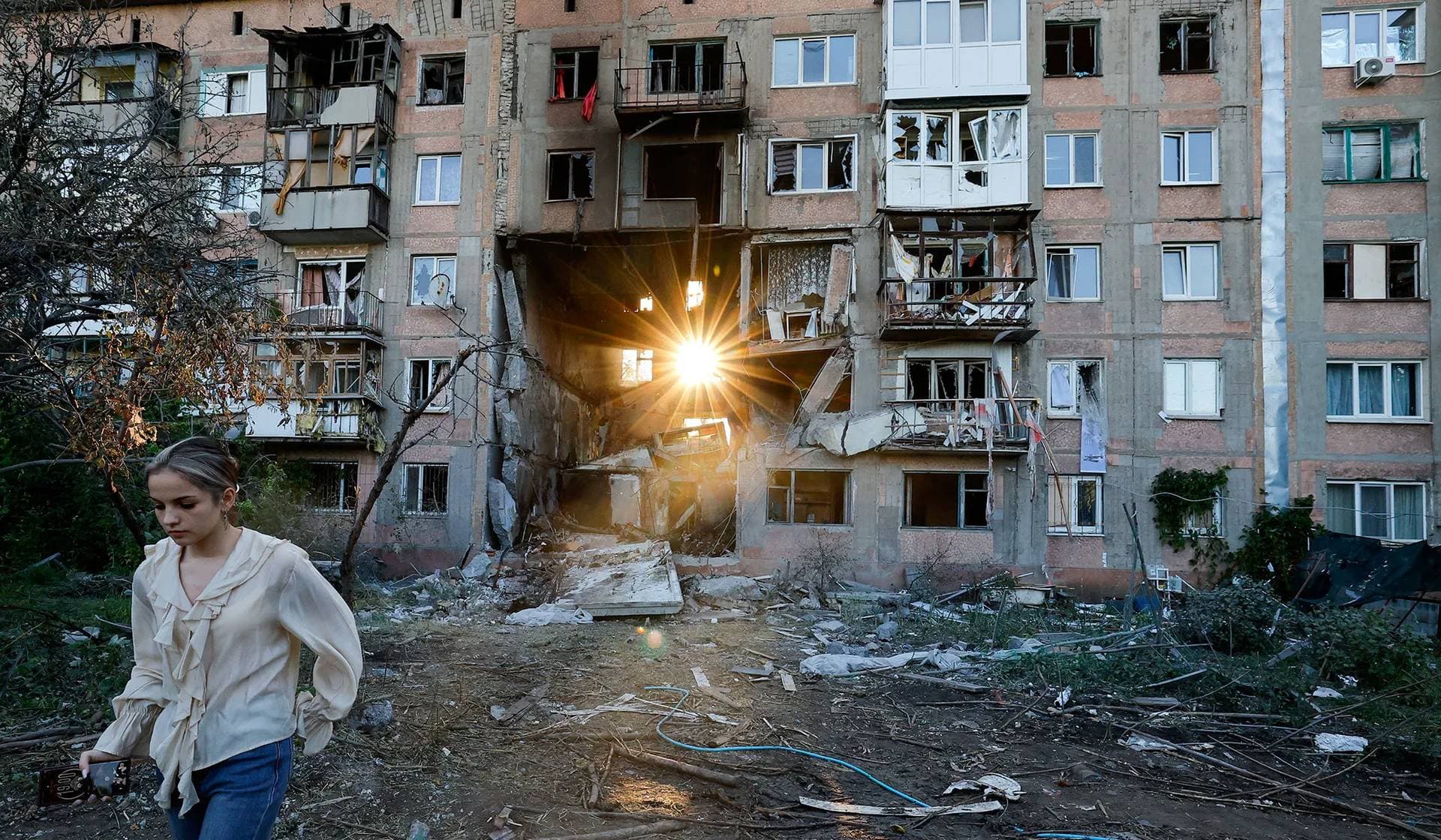 The sun sets behind a heavily damaged multi-story residential building following an overnight attack, what Russian-installed authorities called a Ukrainian drone strike, in Horlivka (Gorlovka)